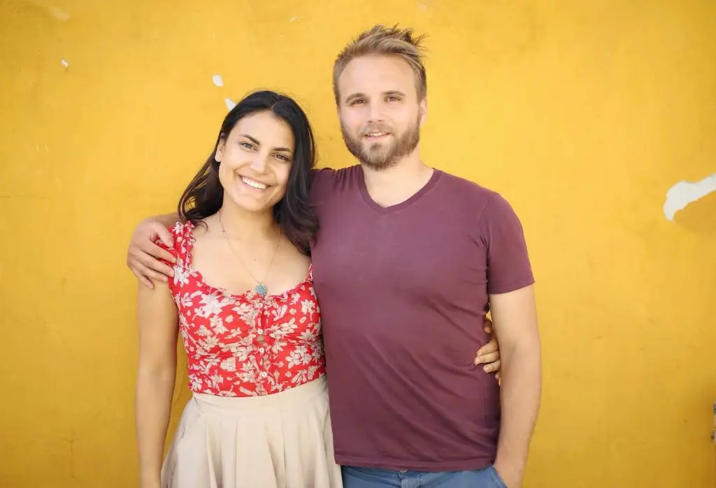 Deborah and Christian Ostmo taking photos against a yellow wall