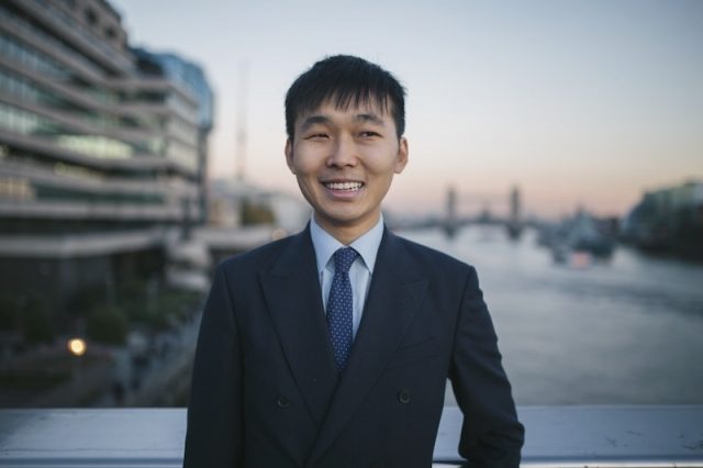 Man wearing a suit poses for photos on London Bridge