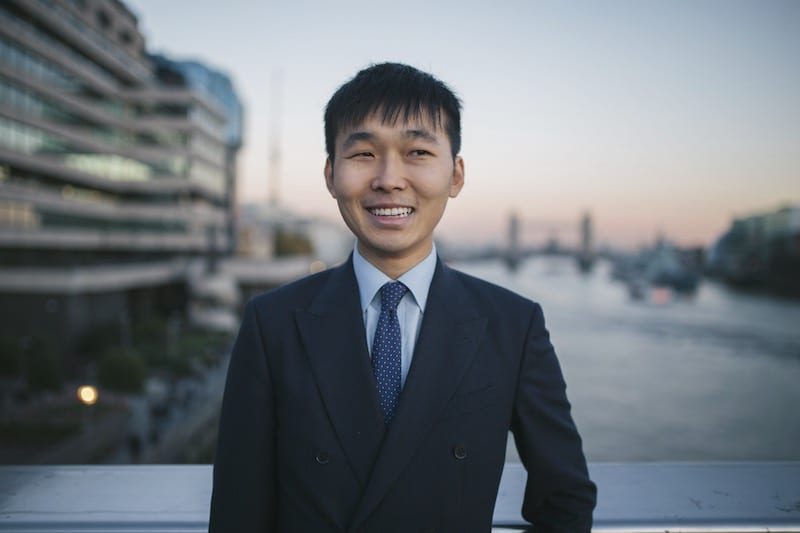 Man wearing a suit poses for photos on London Bridge